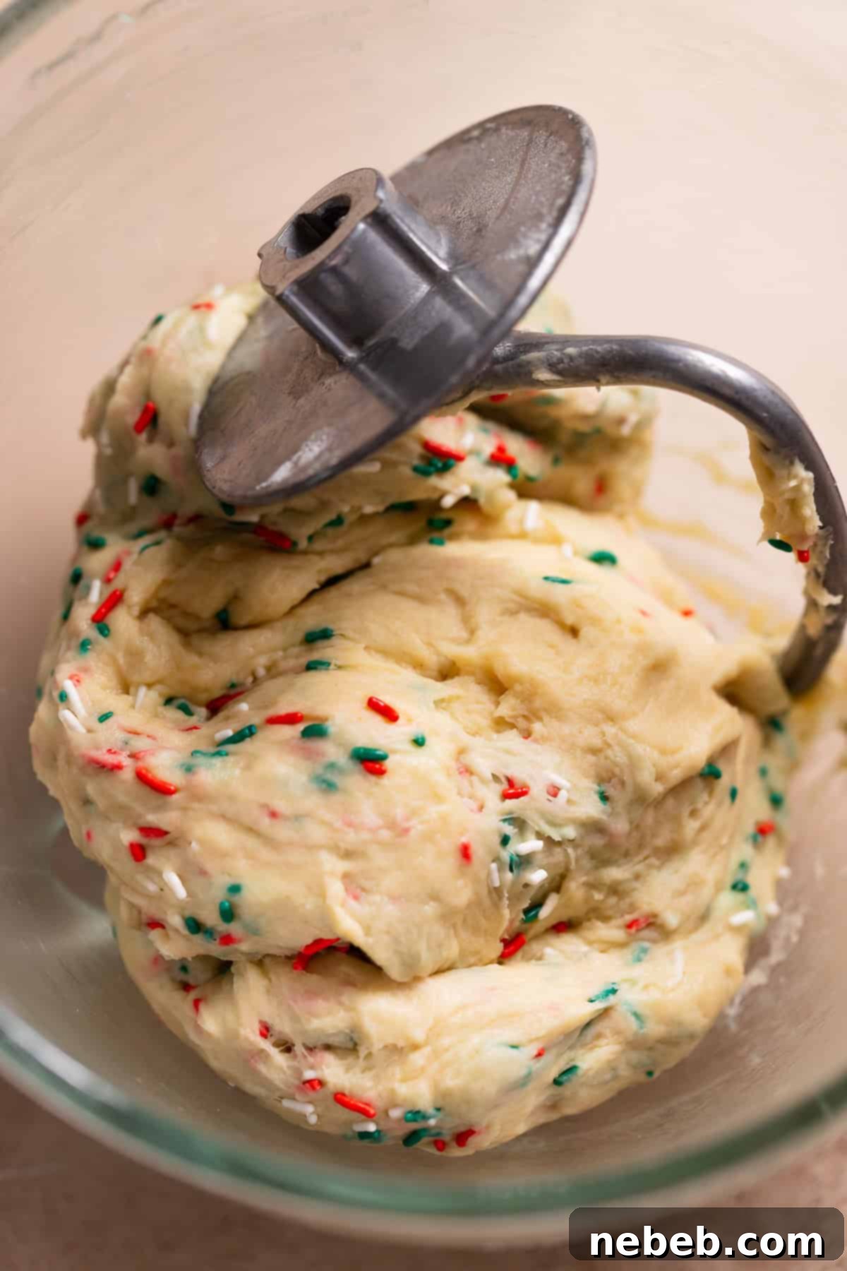 Christmas Swirl Sugar Cookie Bites 4 Sweet roll dough being kneaded in a mixer bowl with vibrant green and red sprinkles.