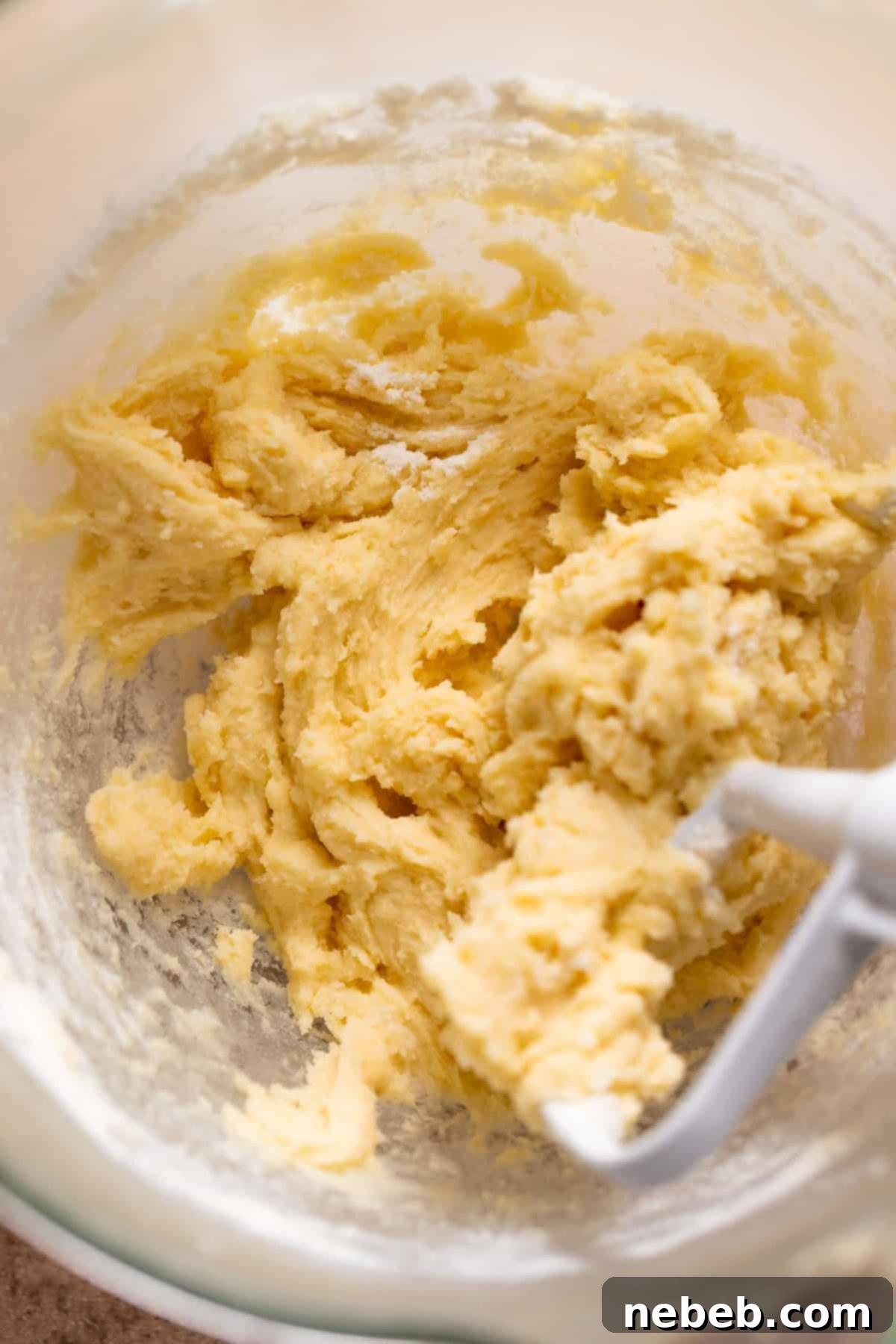 Christmas Swirl Sugar Cookie Bites 5 Sugar cookie dough filling inside a glass mixer bowl with the paddle attachment.