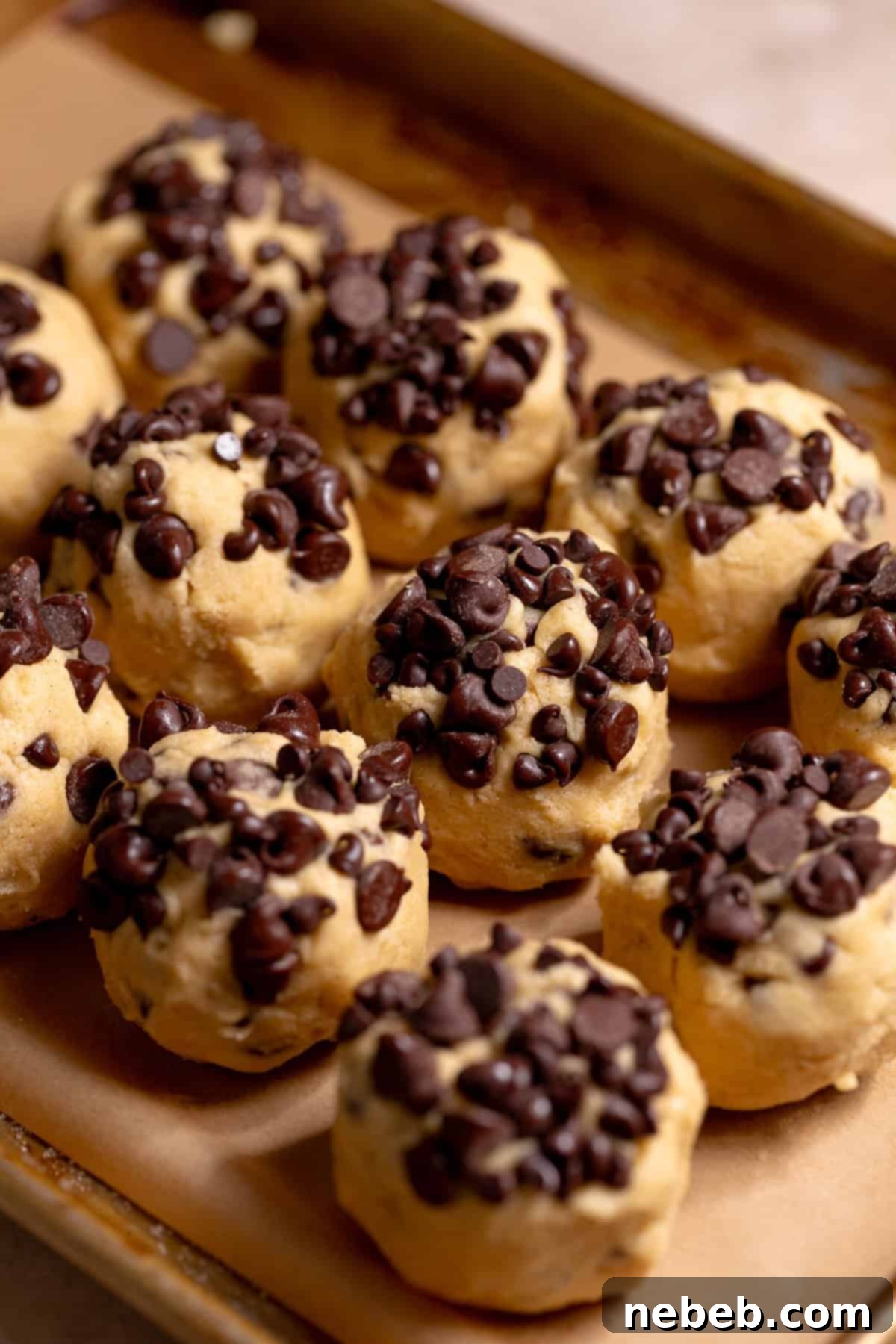Decadent Chocolate Chip Snickerdoodle Dream Cookies 7 Cookie dough balls with chocolate chips on top on a baking sheet.