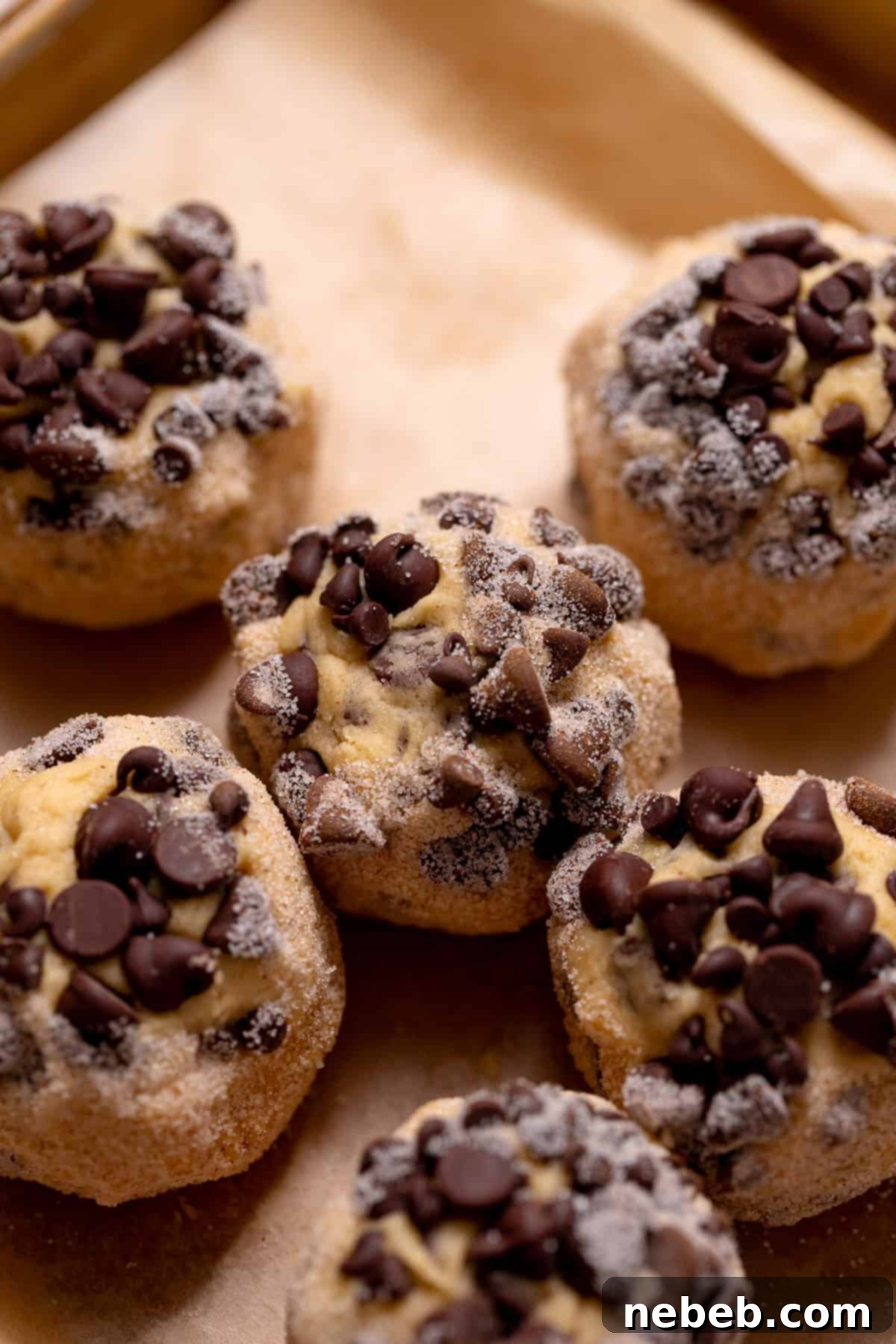 Decadent Chocolate Chip Snickerdoodle Dream Cookies 8 Chocolate chip snickerdoodle dough balls coated in cinnamon sugar on a baking tray.