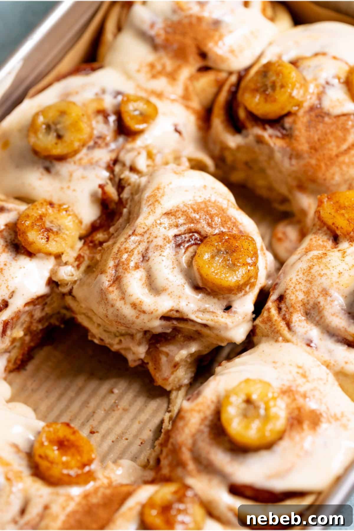 Banana Bread Cinnamon Rolls 2 Freshly baked banana bread cinnamon rolls in a pan with golden brown swirls.