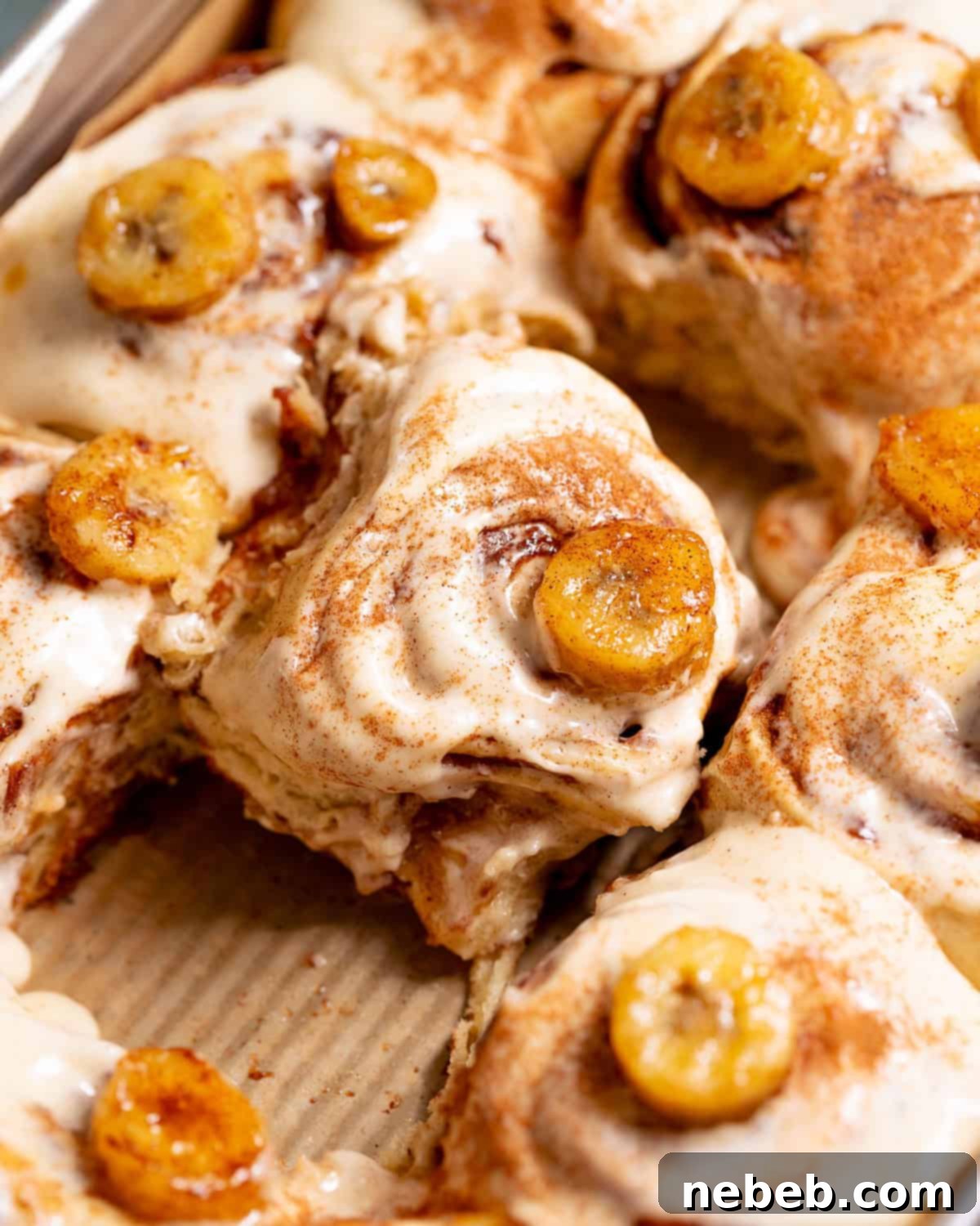 Banana bread cinnamon rolls topped with cream cheese frosting and caramelized bananas.